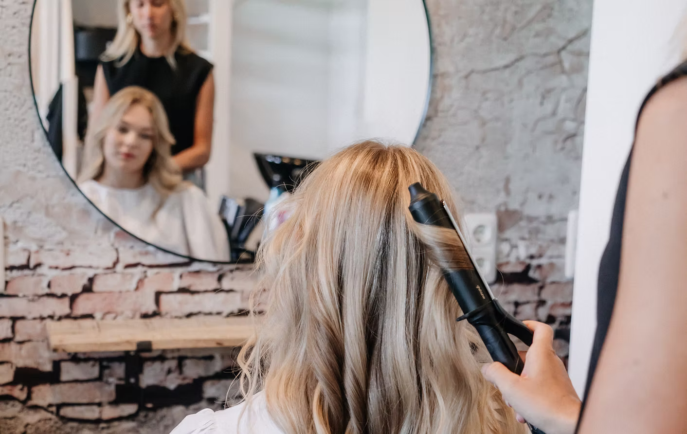 Zacht blond haar met highlights wordt gestyled in de salon